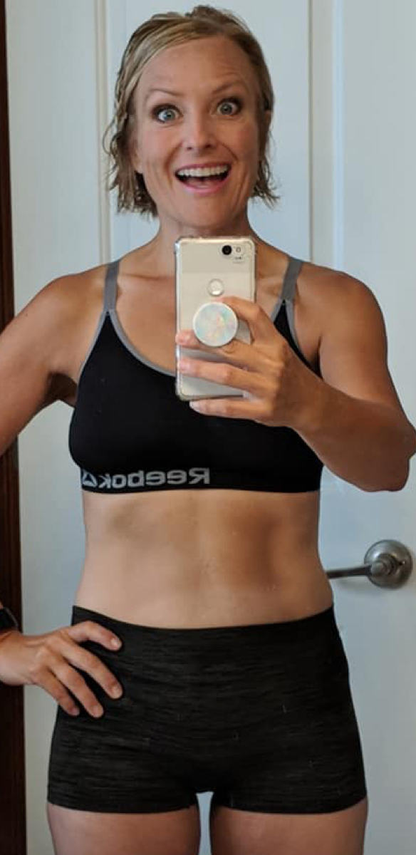Sweaty woman with black tank-top smiling in mirror